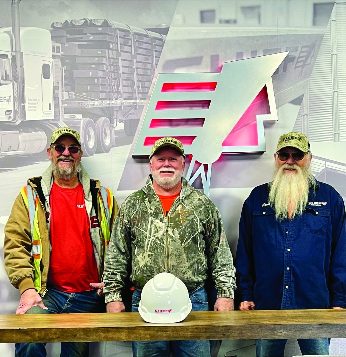 three chief carriers employees standing in front of the logo in front of a hard hat on a wooden narrow table