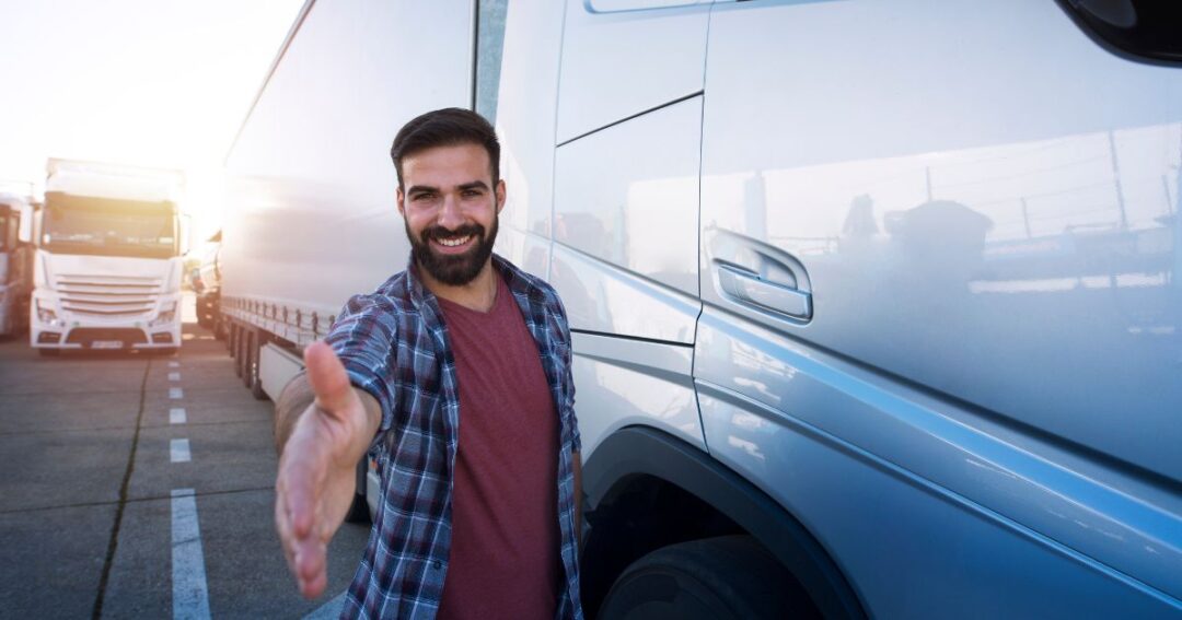 A smiling truck driver extending his hand toward the camera