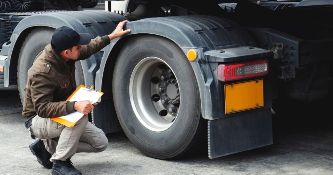 Man with a clipboard inspecting semi-truck tires