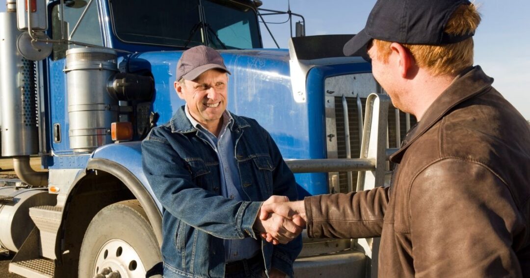 Smiling truck driver shaking hands with man