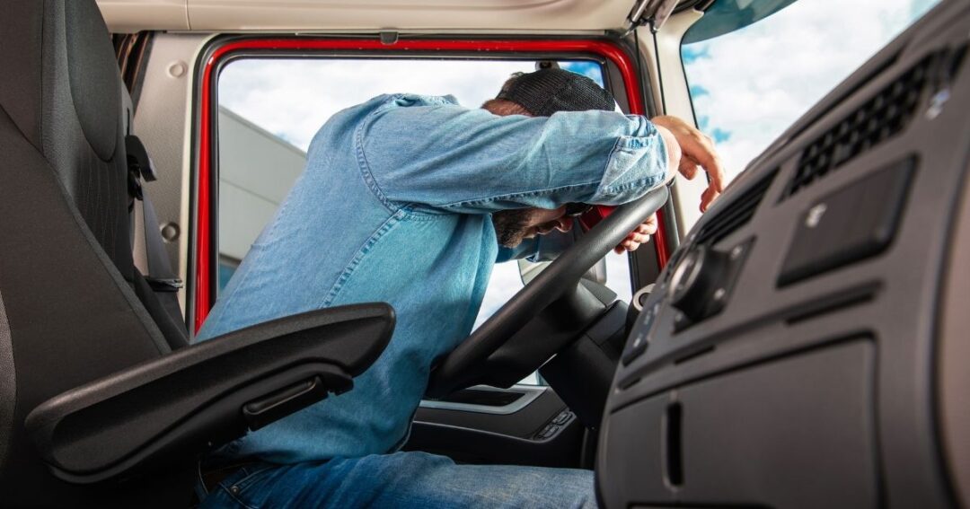 Driver asleep behind the wheel of a semi-truck. Truck driver termination behaviors