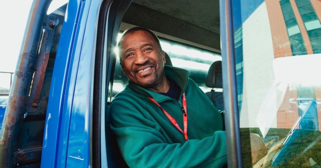 A smiling man behind the wheel of a commercial truck