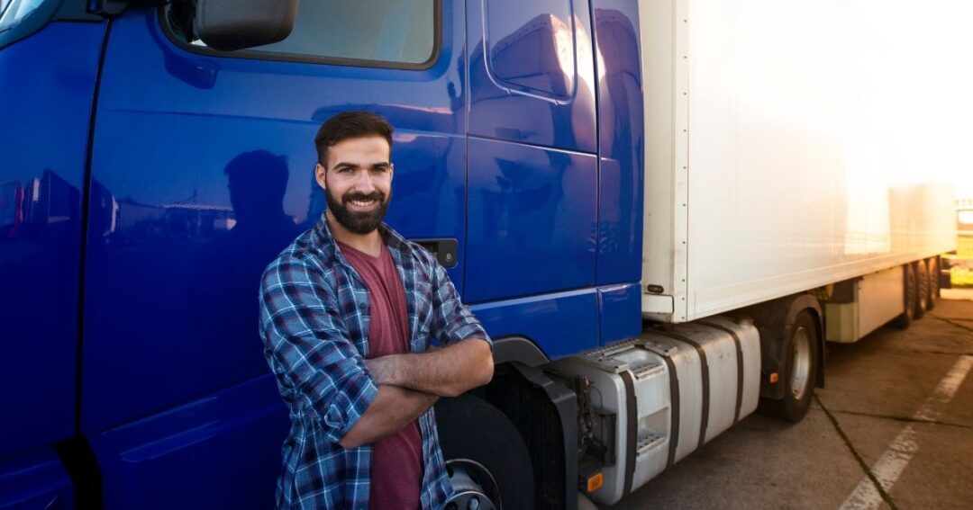 Smiling driver leaning against a semi-truck tractor