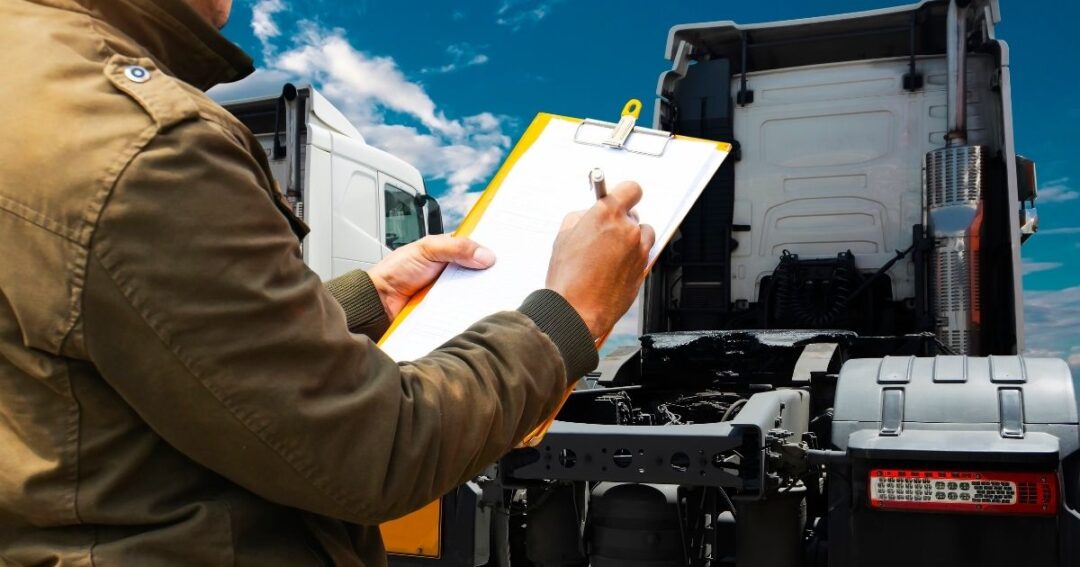 Inspector making notes on a clipboard, semi-trucks in the background