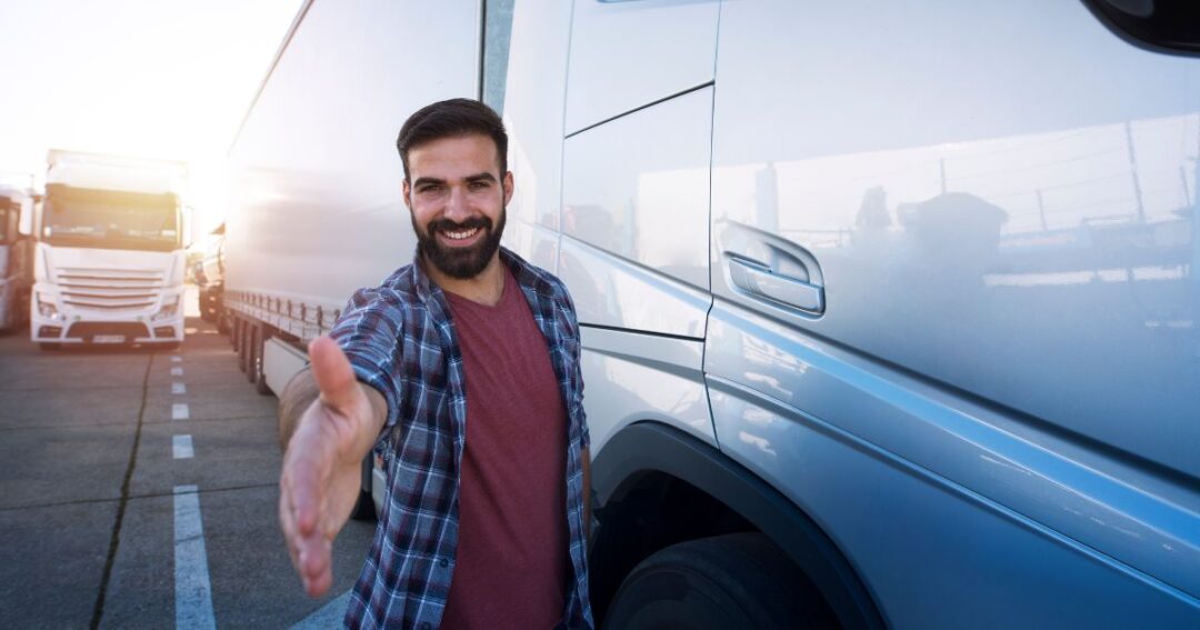 A smiling truck driver extending his hand toward the camera