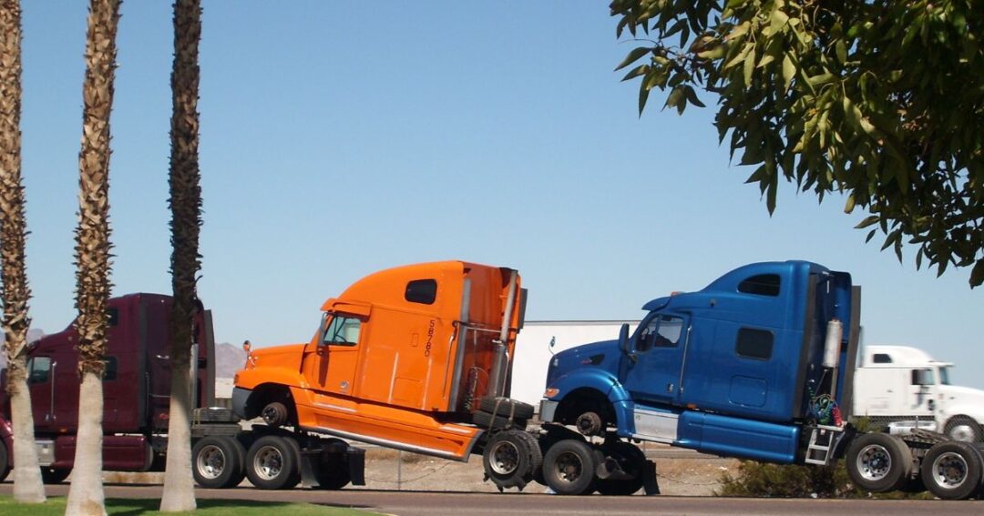 Two semi-truck cabs being towed.