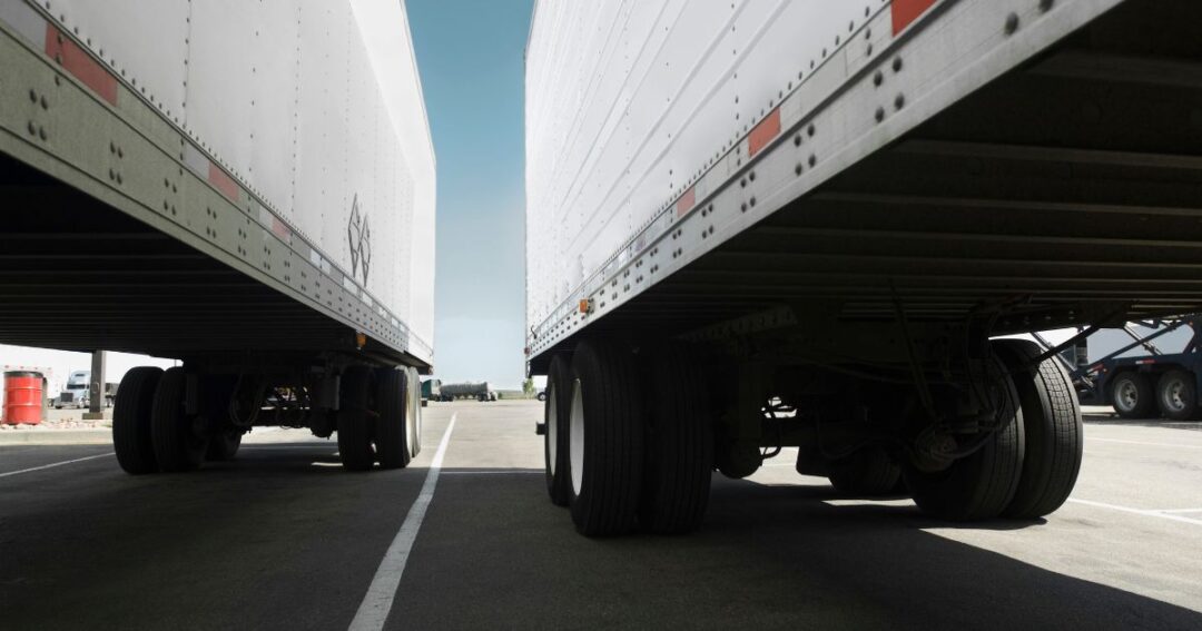 Two semi-truck trailers side-by-side on a paved lot.