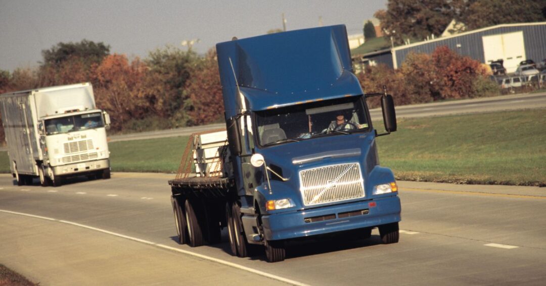 A blue flatbed truck on a highway road.