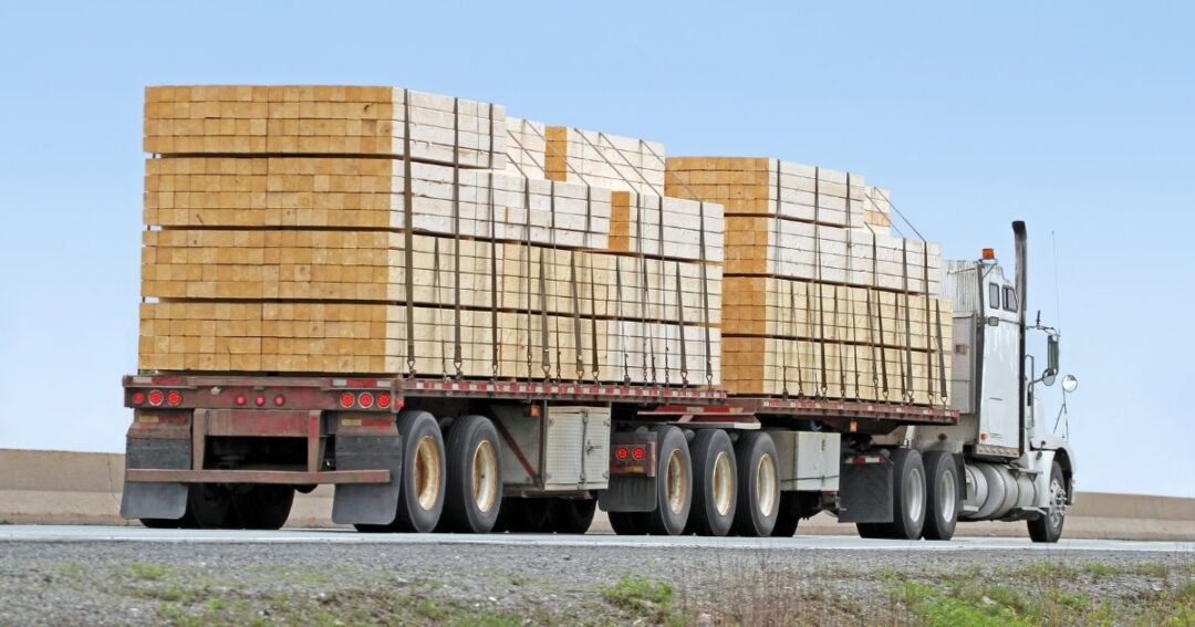 A flatbed truck pulling a load of lumber.