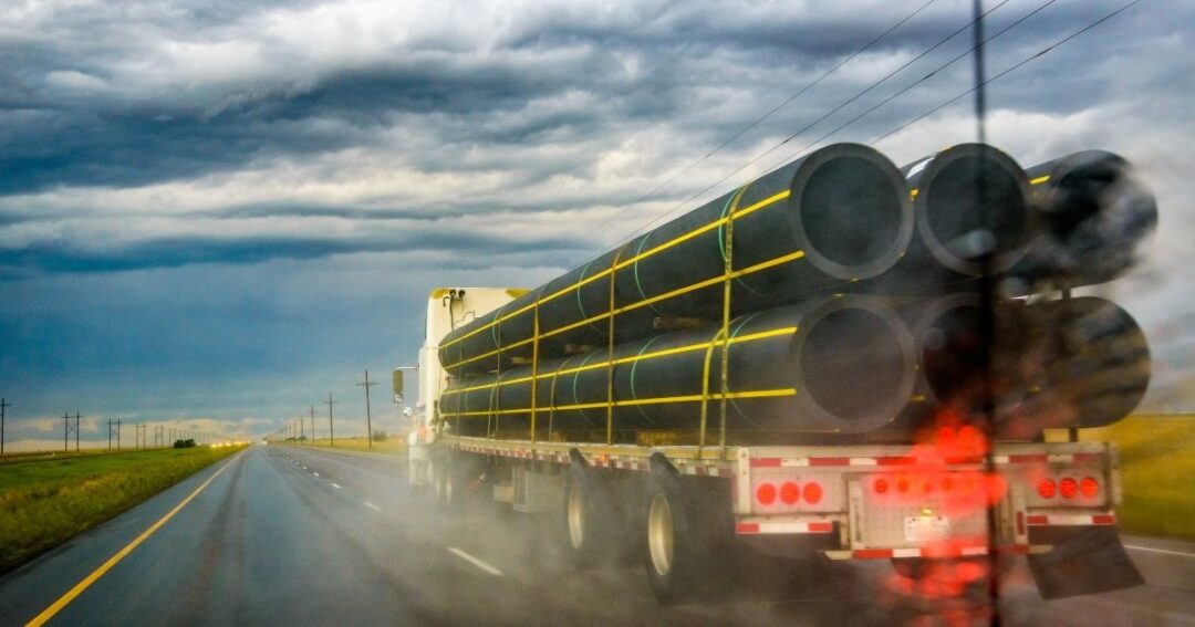 A flatbed truck hauling a load on a highway.
