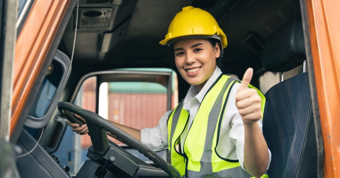 A smiling female truck driver looking at the camera.
