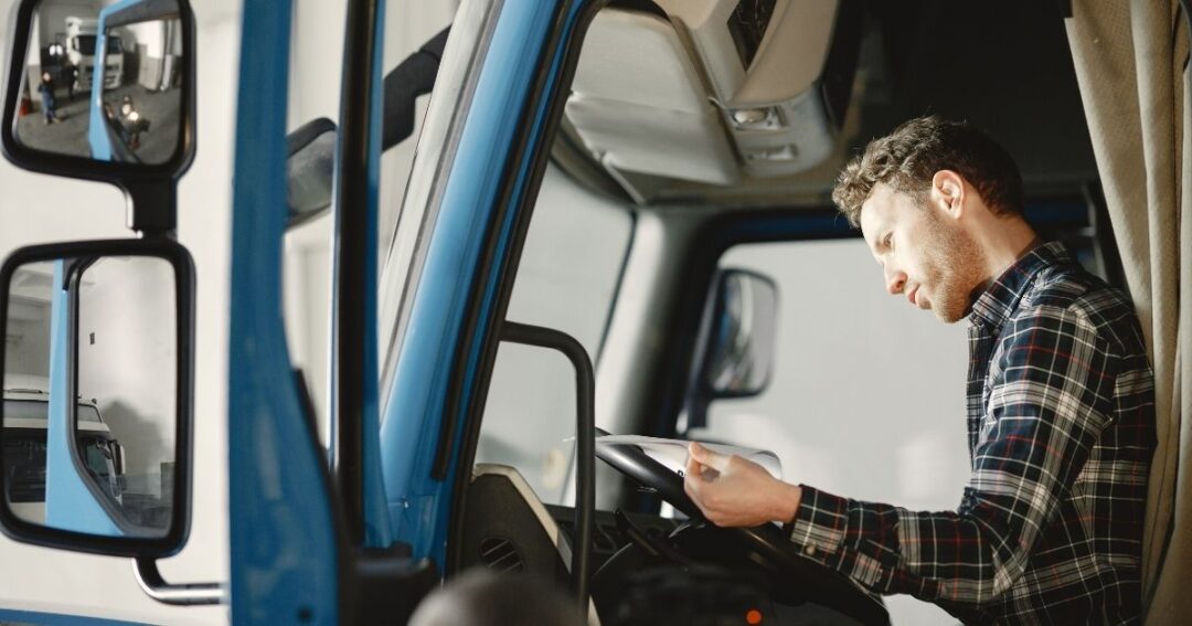 A male truck driver looking over truck maintenance paperwork.