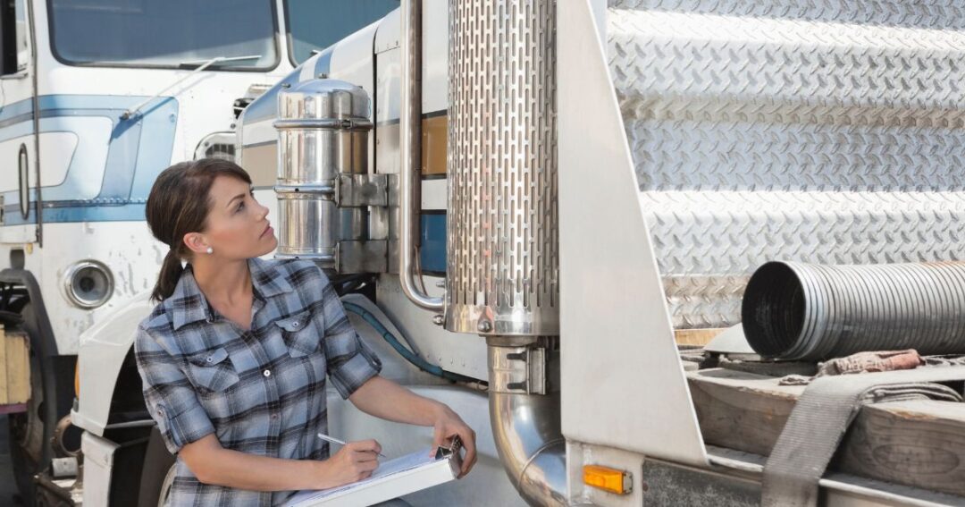 Woman with clipboard inspecting a flatbed truck.