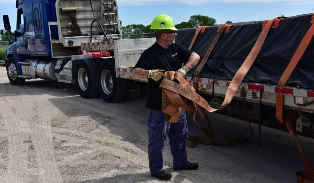 A Chief Carriers driver is securing a load with straps.