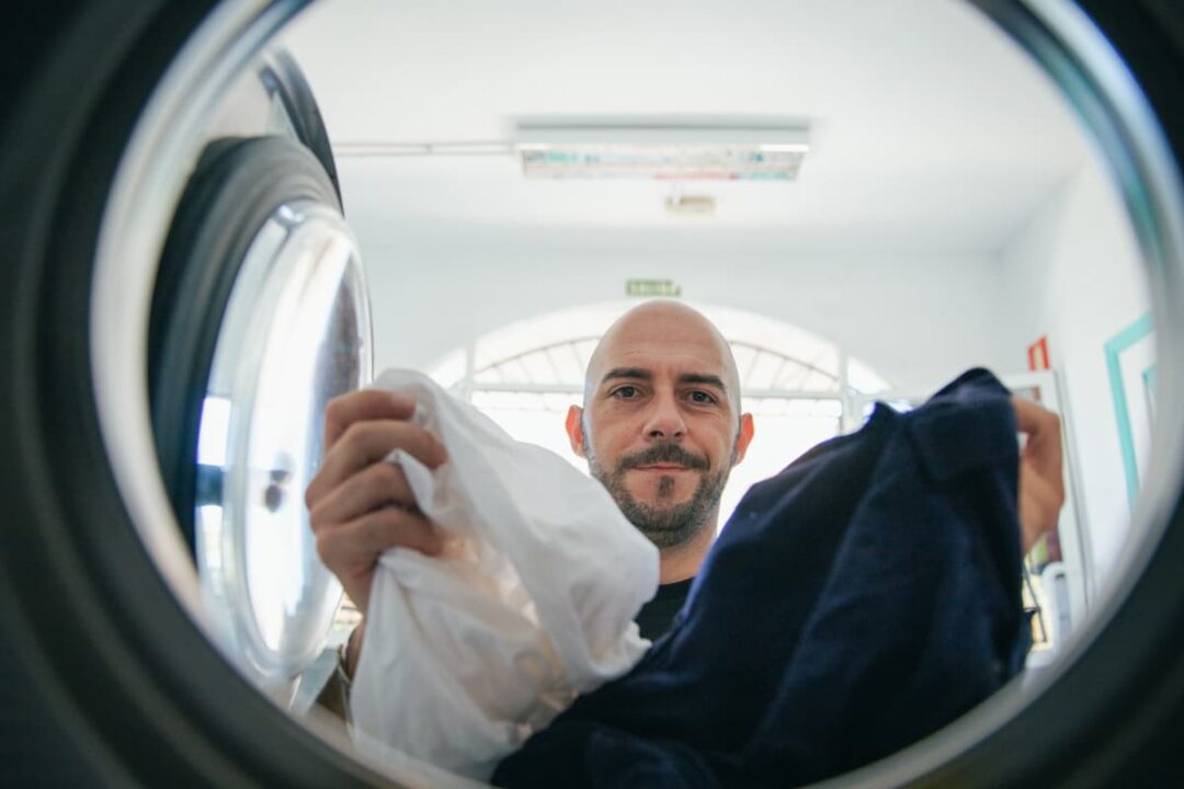 A man putting laundry into a laundromat washing machine.