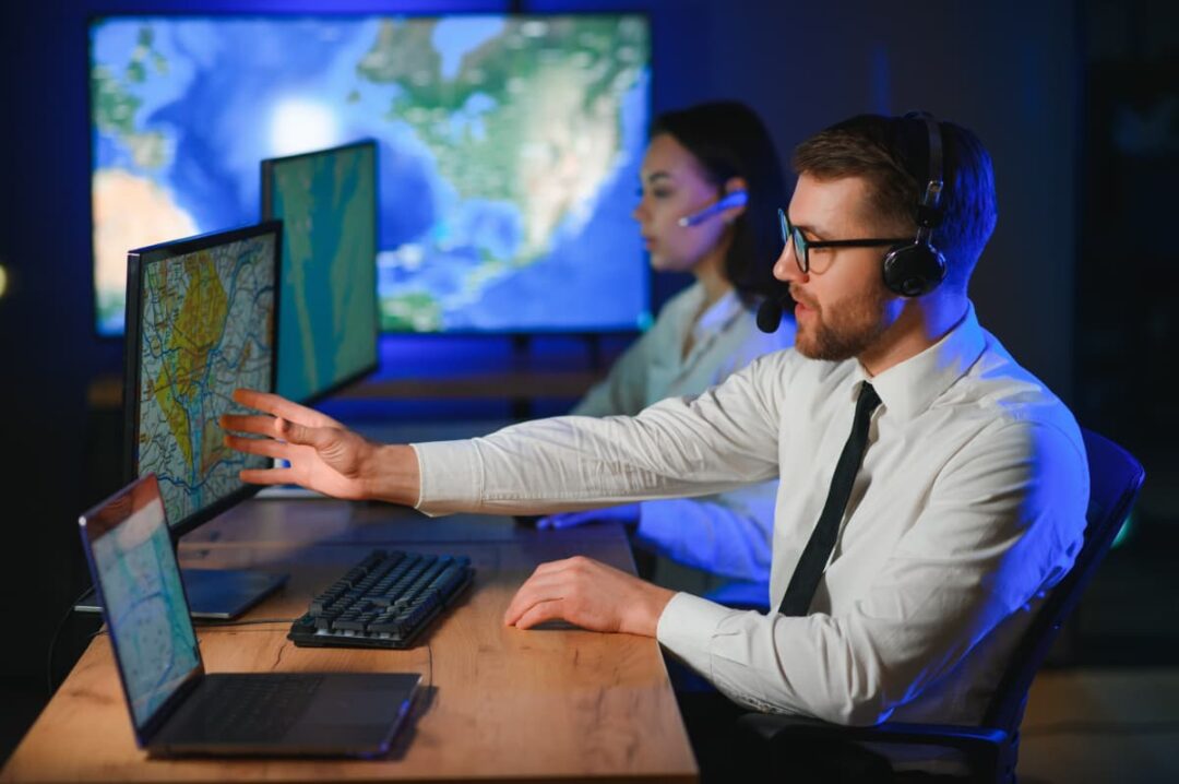 Dispatch team members consulting maps on their computer monitors.