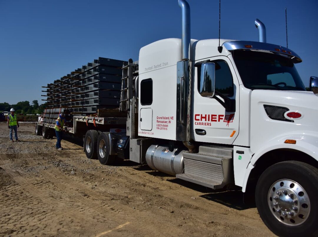 Two Chief Carriers drivers are checking the securement of a flatbed truck load.
