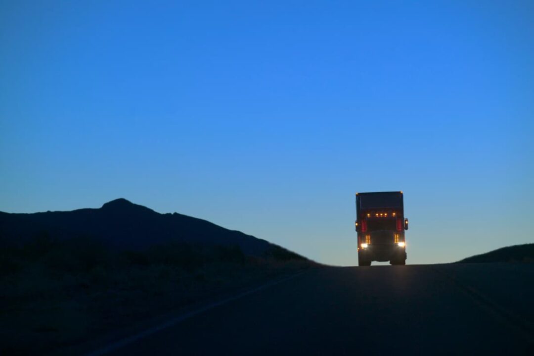 A semi truck driving at night.