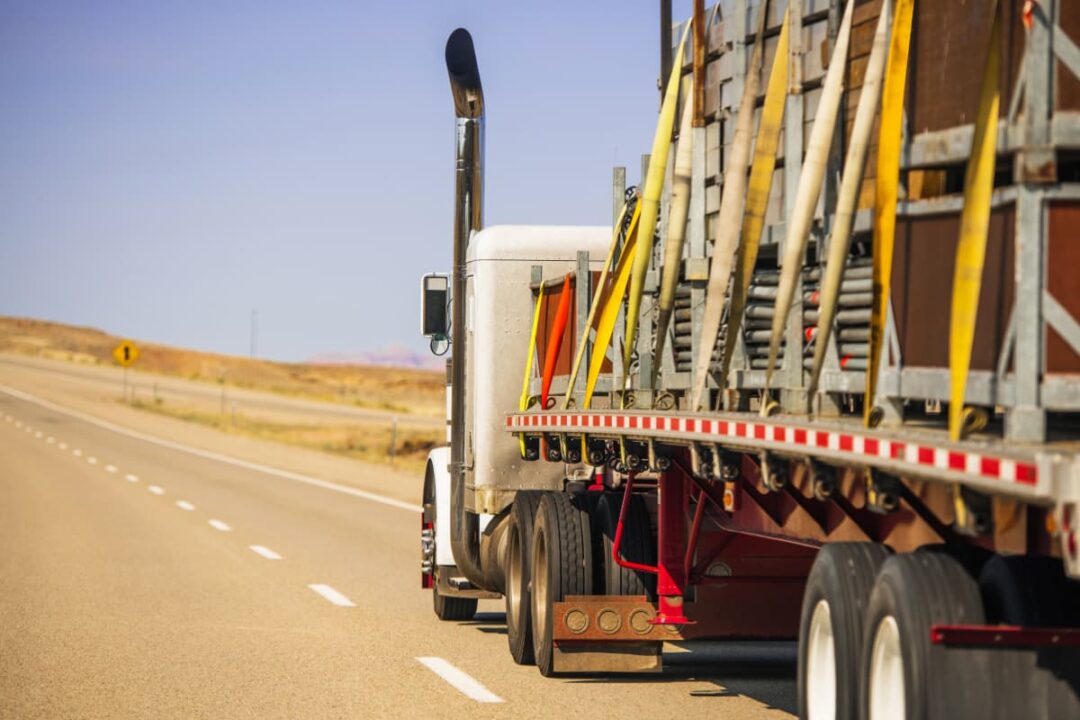A loaded flatbed truck on a highway.