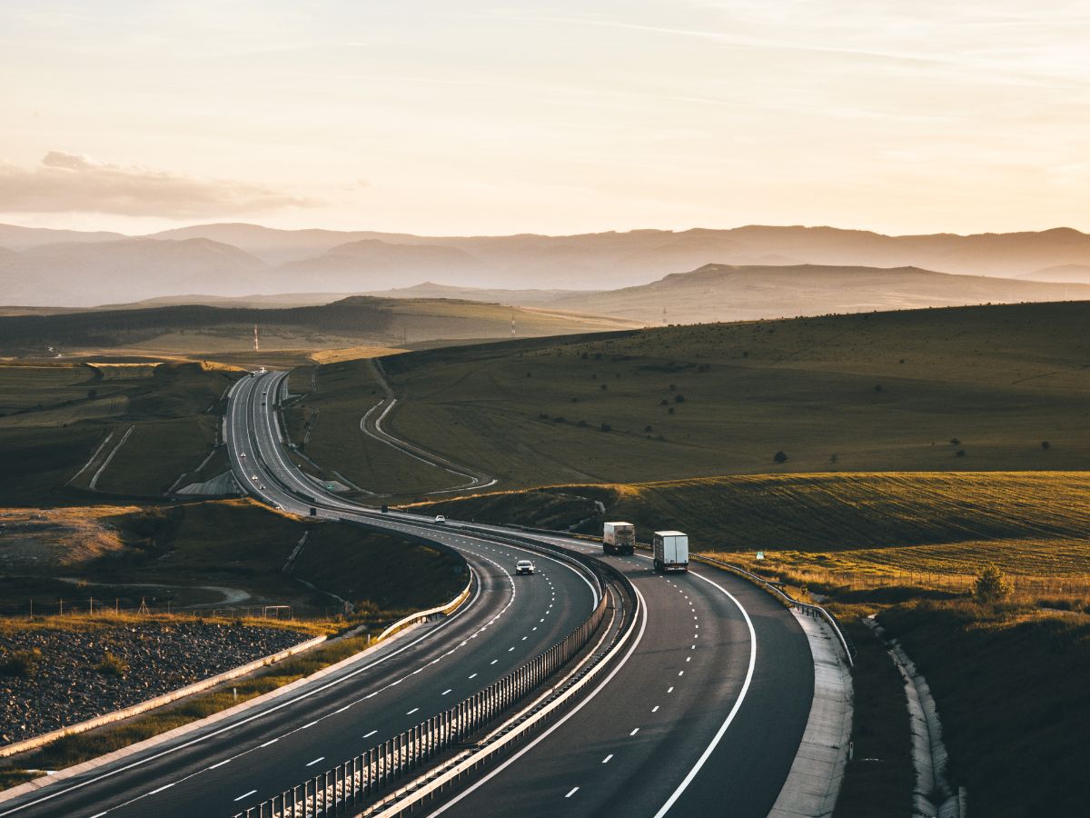 Two commercial trucks on an open highway road.
