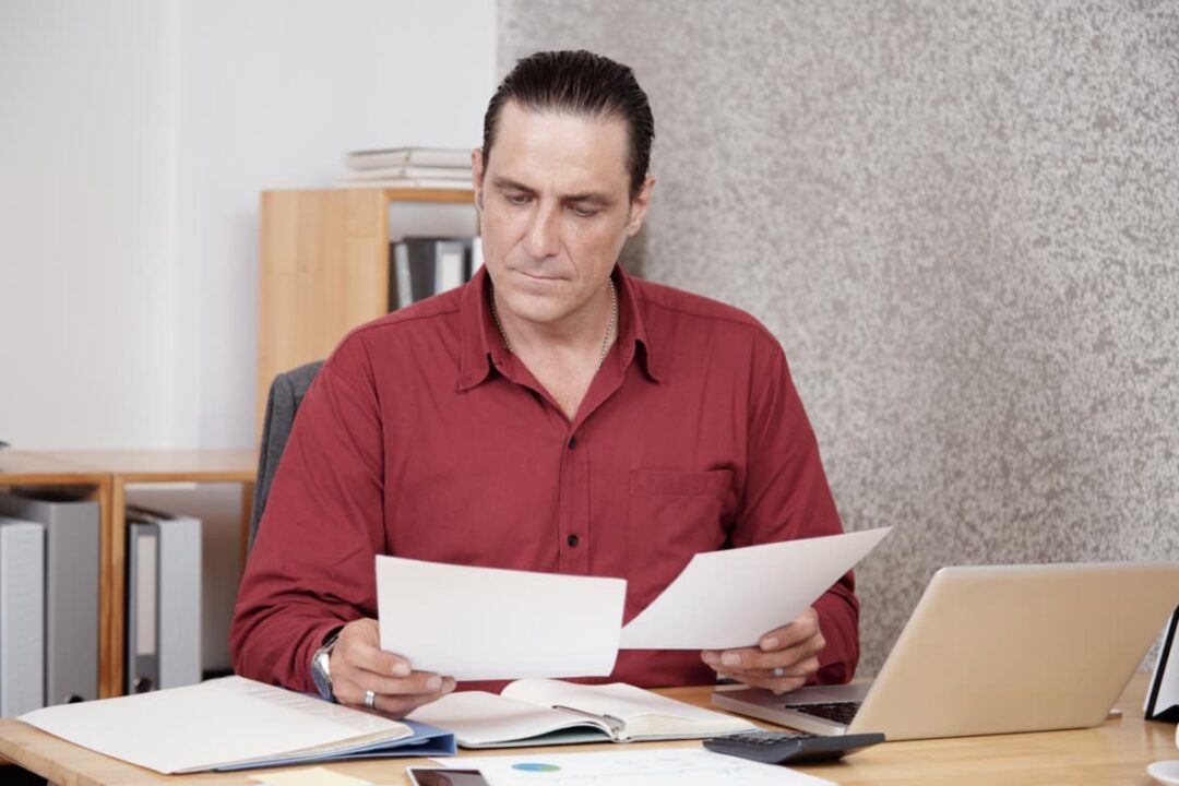 Man sitting at his desk looking over paperwork.