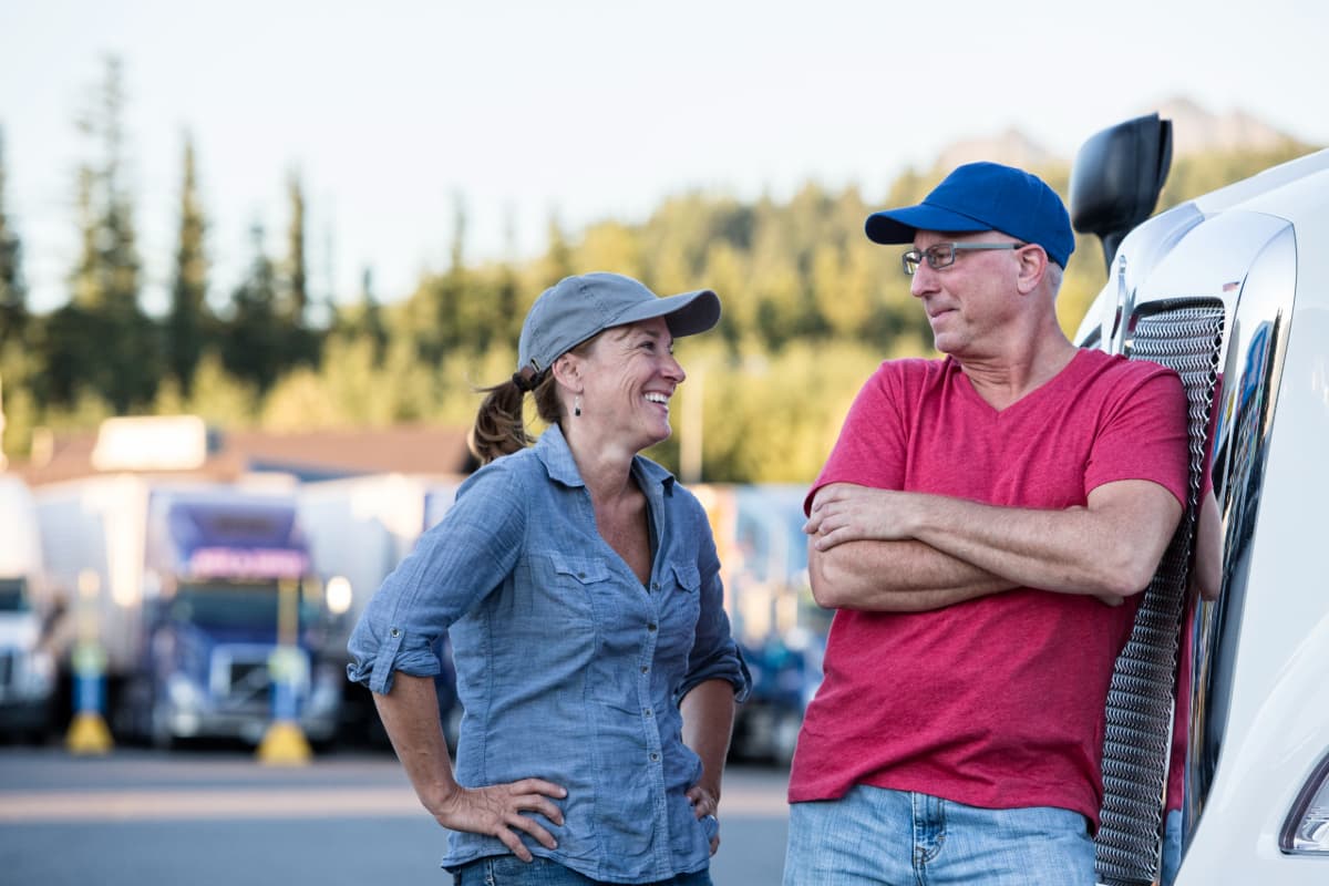 A smiling husband and wife truck driving team at a truck stop.