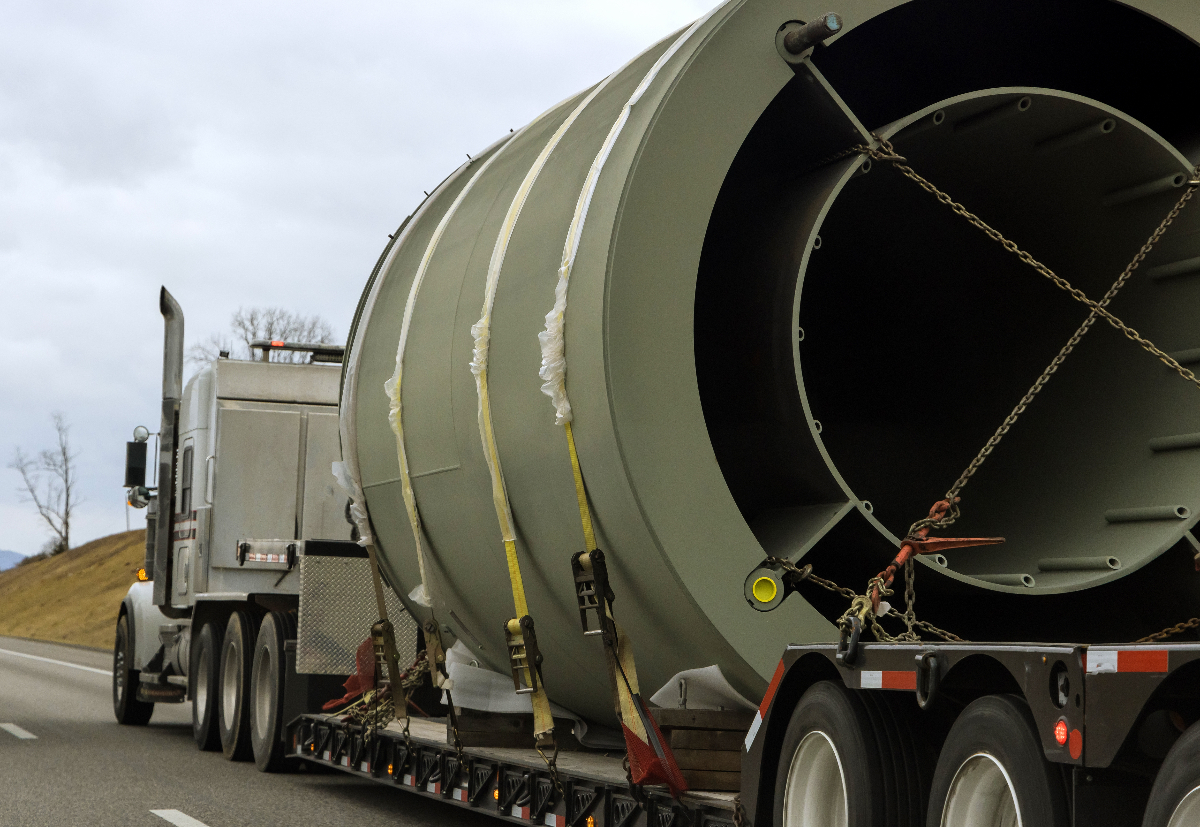 A flatbed truck transporting oversized cargo by highway.