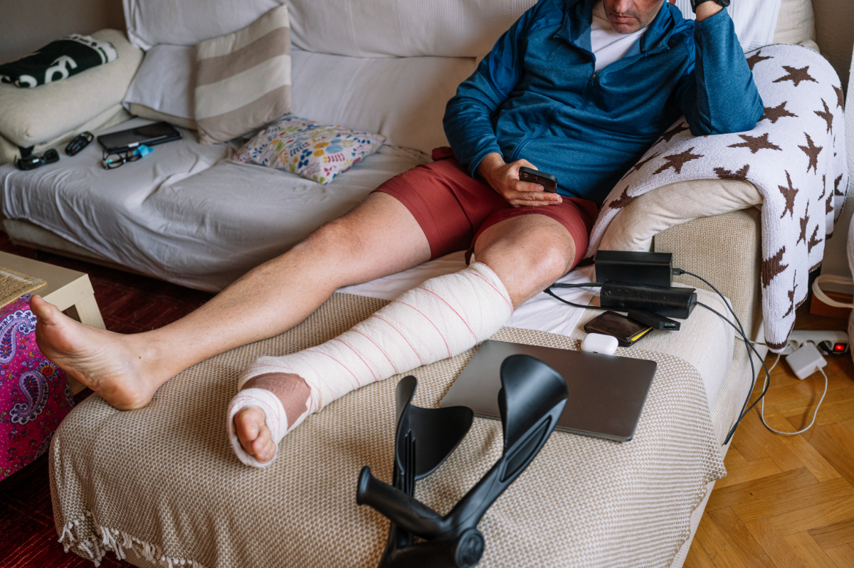 An unidentified man with an injured leg on his couch at home.