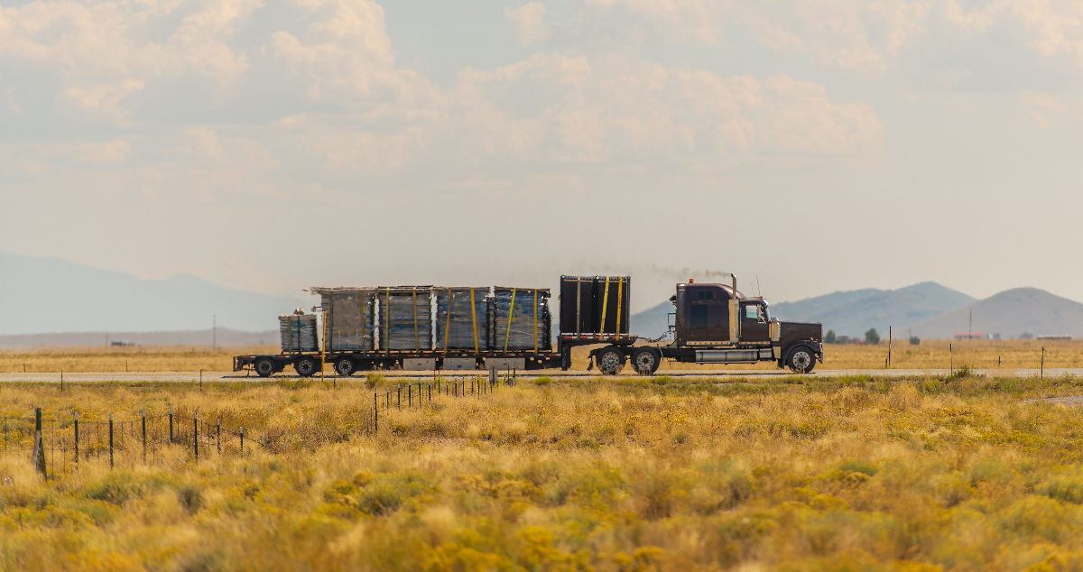 A flatbed truck with a full load on a highway.