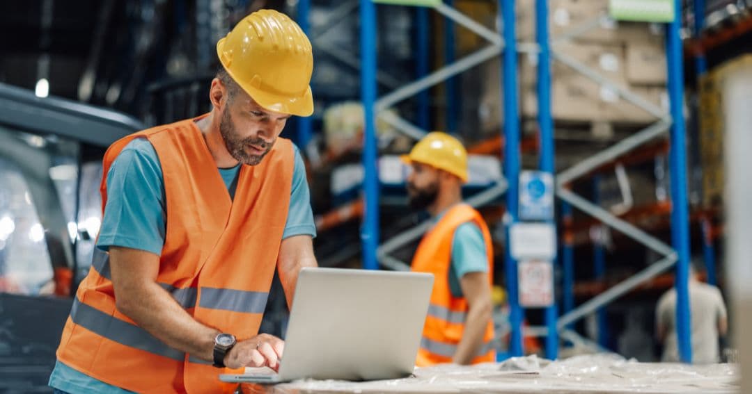 Industrial worker using laptop to track status of shipment.