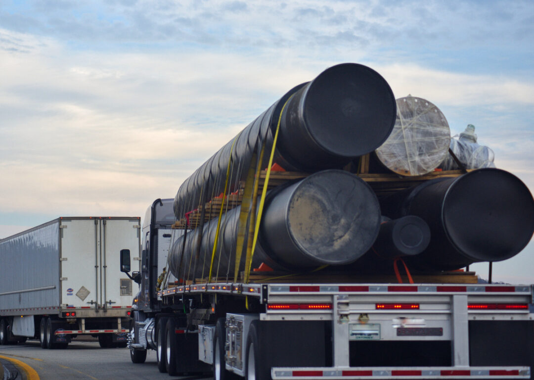 A truck with an oversized flatbed load on the highway.