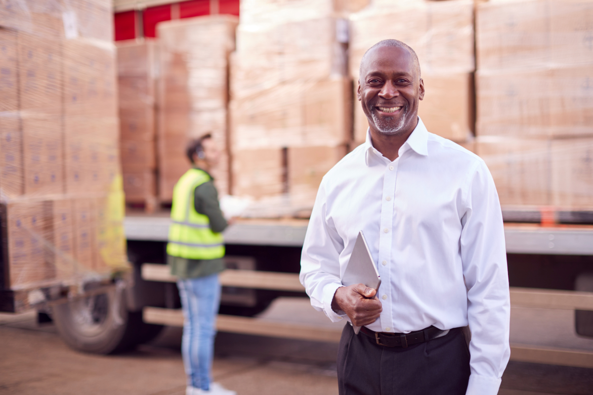 A smiling manager or supervisor in a trucking company setting.