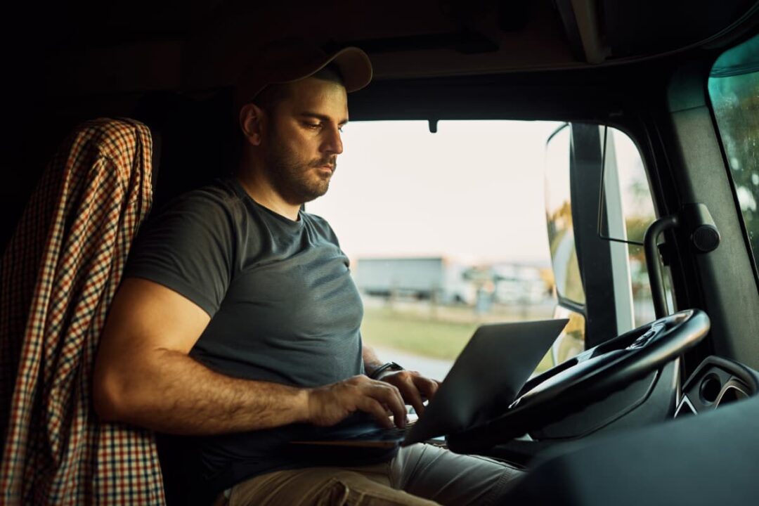 A truck driver on a laptop updating records.