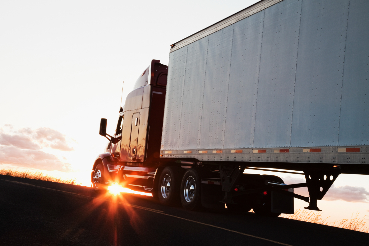 A semi truck backlit by the sun.