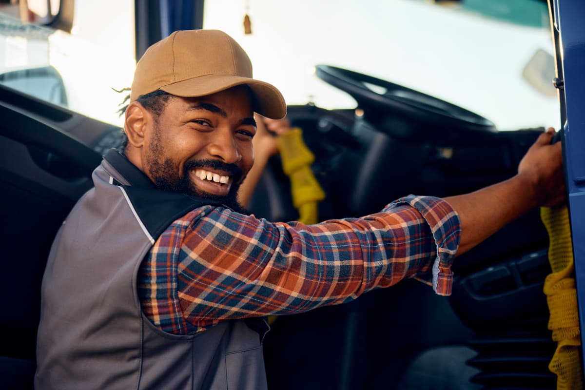 A smiling truck driver getting into his commercial truck.