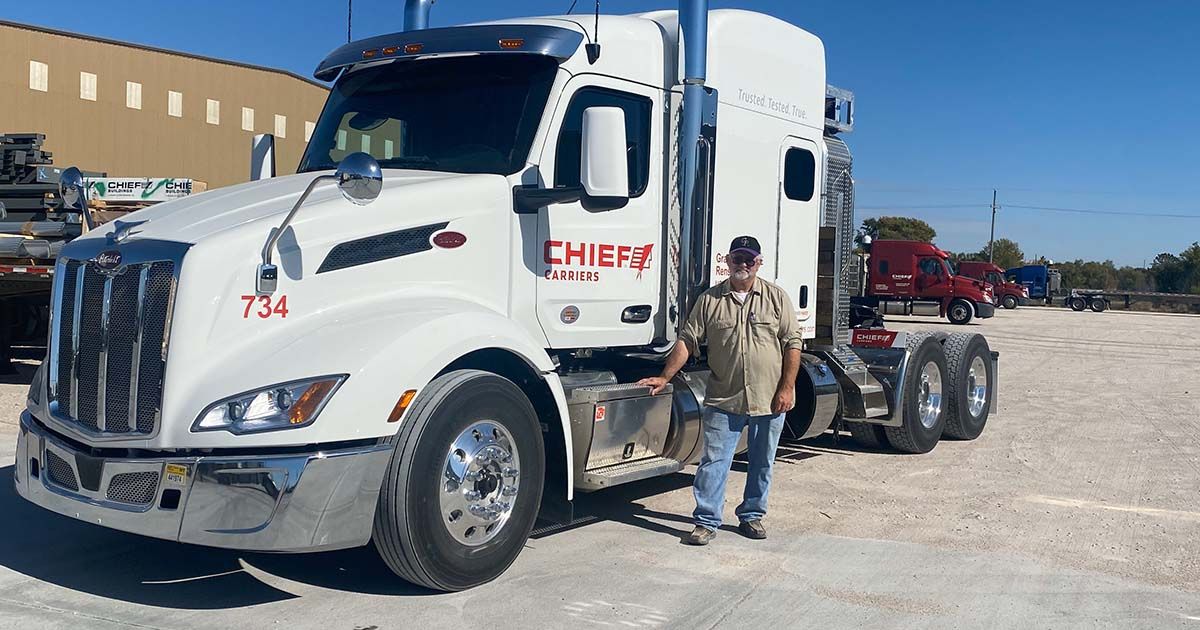 A Chief Carriers driver standing next to a white company truck.
