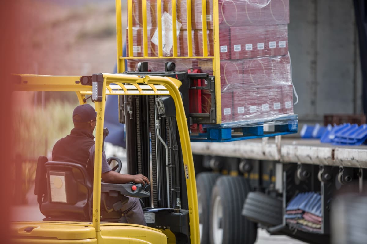 Forklift operator loading freight onto a flatbed trailer.