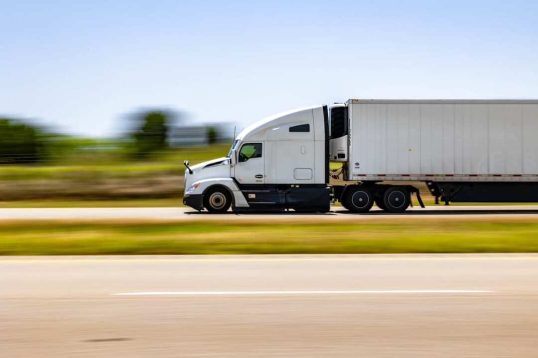 View of a semi truck driving by on a highway.