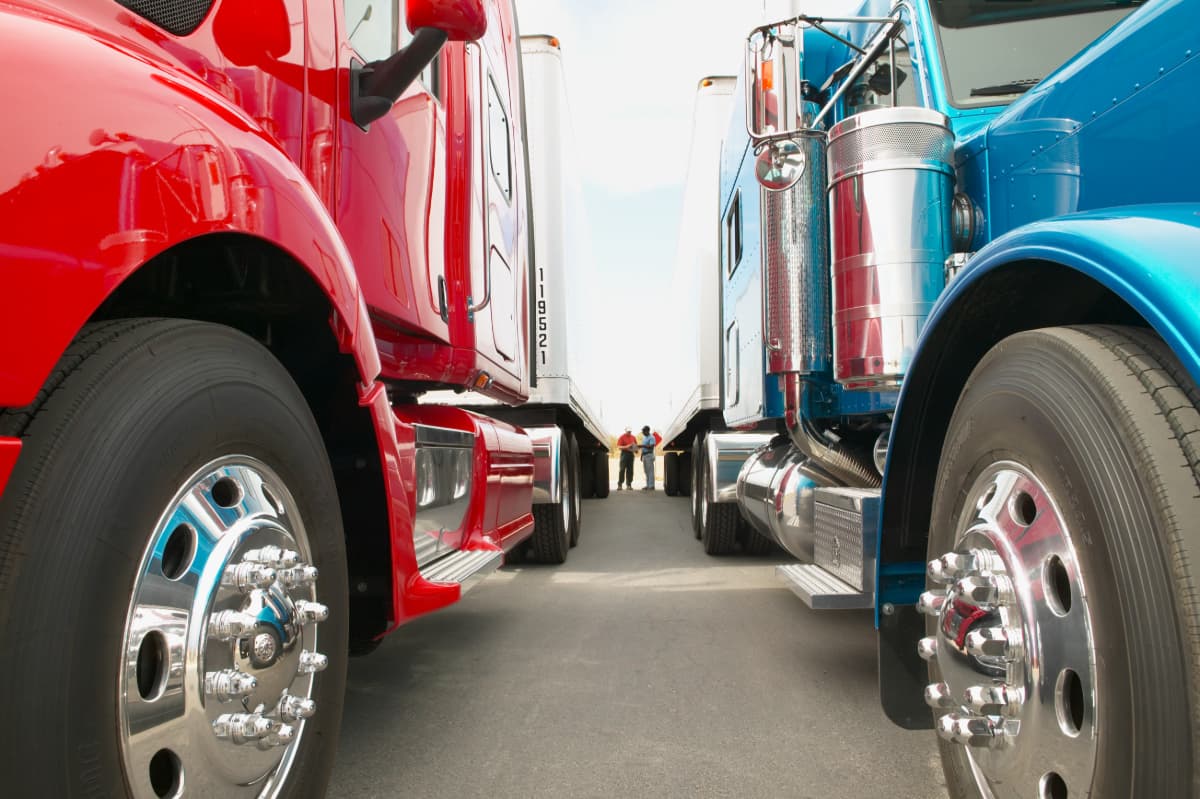 A view between two semi trucks that shows two men talking