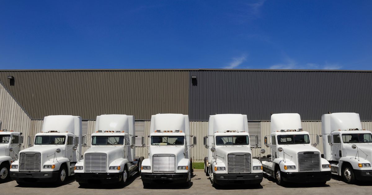 A parking lot with semi trucks sitting idly.