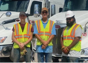 3 employees in front of truck.