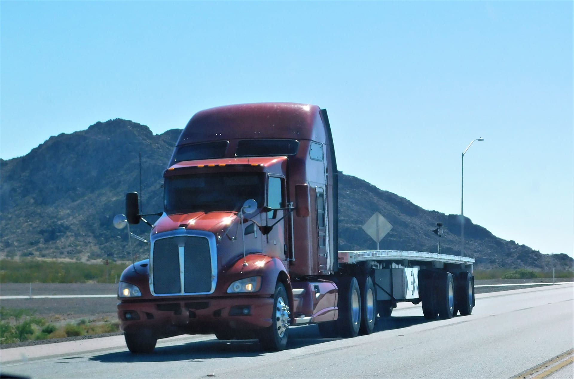red semi with no load on a flatbed trailer